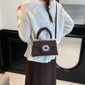 Dark brown satin small square handbag with rhinestone buckle worn by a model in casual style