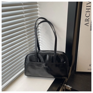 Minimalist black PU leather pillow tote bag with front pocket and zip closure in macro view