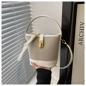 Detail of cream woven bucket bag with white leather trim and gold-tone metal hardware