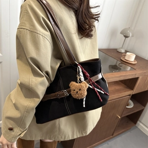 Chic black canvas tote bag with brown leather straps and a cute teddy bear charm