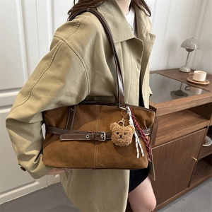Brown suede tote bag with leather buckle and teddy bear charm shown on a model