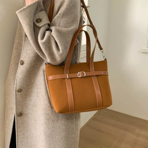 Brown bucket bag with strap detail shown on a model wearing a wool coat