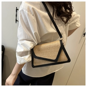 Close-up of the woven straw texture and black faux leather trim on the crossbody bag