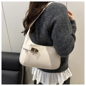 Close-up of white leather underarm bag featuring elegant golden hardware and buckle