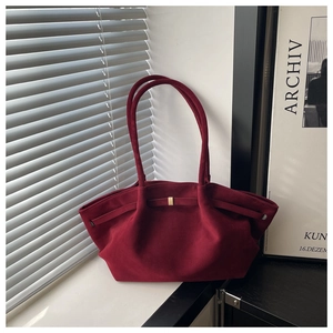 Macro detail of wine red suede tote bag with wave-edge design and gold buckle