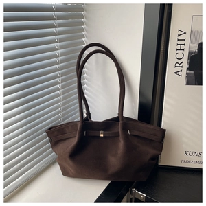 Detail of dark brown suede tote bag with golden metal buckle and aesthetic shadow