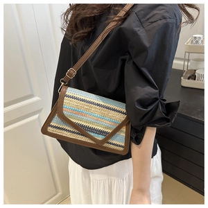 Detail view of rainbow straw bag with brown leather trim and golden metal buckles
