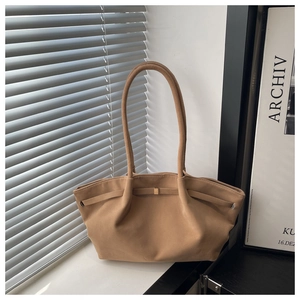 Close-up of camel suede tote bag featuring a leather strap and square metal buckle detail