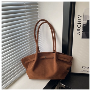 Detail of brown suede tote bag with golden metal buckle and side pleats texture