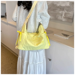 Detail of light yellow nylon tote bag with artistic embroidery and yellow ribbon bows