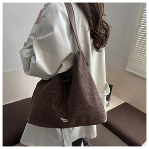 Close-up of leopard print tote bag with brown leather strap and suede texture detail