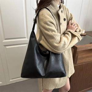 Minimalist black large capacity PU leather tote bag worn by a model in a beige coat