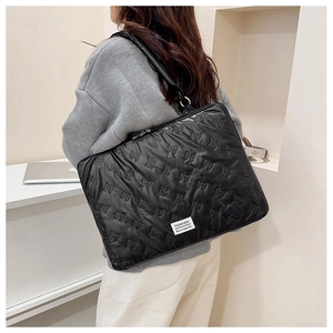 Detail of black quilted laptop sleeve featuring embossed bows and FASHION label