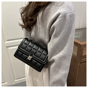 Detail of classic black quilted chain bag with silver twist-lock closure on model