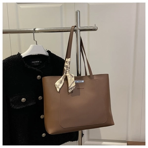 Sac cabas en similicuir marron avec détail de foulard en soie accroché sur un cintre
