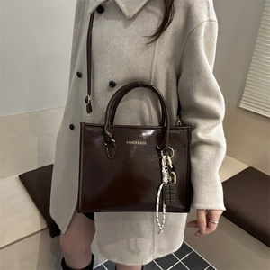 Fashionable dark brown glossy tote bag with gold lettering and adjustable shoulder strap