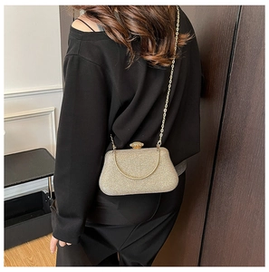 Close-up of golden shimmer evening clutch with chain strap and elegant metal top handle