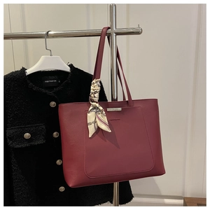 Détail du sac cabas en cuir rouge vin avec foulard décoratif et poche avant élégante