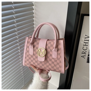 Close-up of pink crossbody bag with M-letter monogram pattern and gold metal buckle