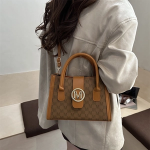 Stylish brown monogram crossbody bag with gold M buckle and adjustable strap