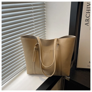Detail of minimalist beige PU leather tote bag with exterior pocket and adjustable strap