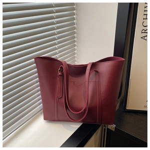 Macro view of burgundy leather tote bag showing adjustable straps and matte texture