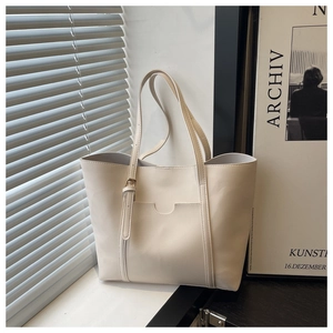 Detail of minimalist cream tote bag with metal buckle and sunlit shadow effect