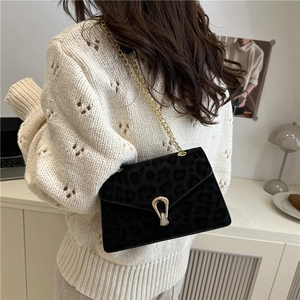 Sac bandoulière rétro à imprimé léopard noir avec chaîne dorée porté par un modèle