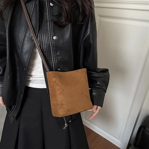 Sac seau en daim marron minimaliste porté en bandoulière avec une sangle fine