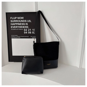 Detail of black tote bag set with suede patchwork texture and gold leather lettering