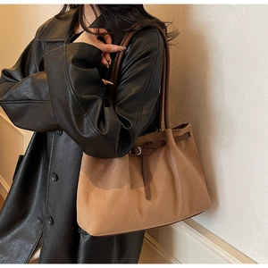 Detail of vintage brown suede tote bag with slim strap and silver buckle on model
