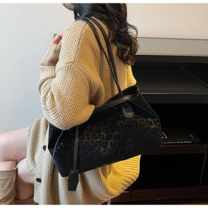 Detail of large black leopard print tote bag with leather straps on model shoulder