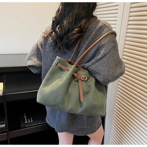 Macro detail of dark green suede bucket bag with leather strap in a vintage room
