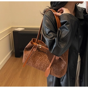 Side view of a vintage leopard print tote bag with brown leather straps on a black coat