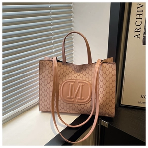 Detailed view of luxury tote bag with elegant M letter pattern and embossed logo medal