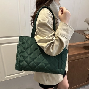 Large dark green quilted tote bag with diamond pattern shown on model shoulder