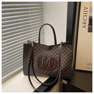 Detail view of the vintage brown tote bag with all-over M-pattern and leather patch