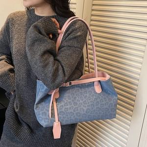 Blue leopard print tote bag with pink straps worn by a model in a minimal setting