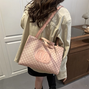 Pink tote bag with all-over M monogram pattern and embossed logo shown on model shoulder