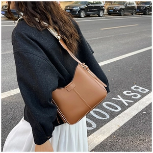 Photo de rue d'un sac seau marron avec une large bandoulière géométrique tissée