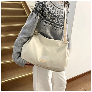 Cream leather tote bag with brand logo tag shown on a model in a casual urban style