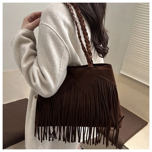 Close-up of bohemian dark brown fringe shoulder bag with woven strap and suede texture