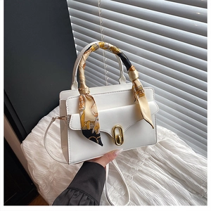 Close-up of white PU leather handbag with golden oval twist lock and printed silk scarf handle