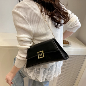 Minimalist black leather crossbody bag with golden M buckle and elegant chain strap