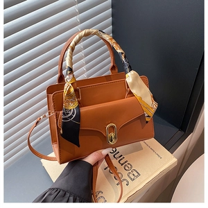 Detail of caramel PU leather handbag with silk scarf handle and golden twist lock