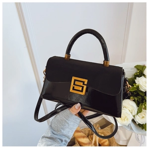 Detail of black leather square bag with suede flap and gold S-shaped metal buckle
