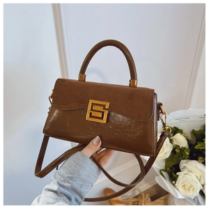 Detail of vintage brown shoulder bag showing suede and patent leather contrast with gold buckle