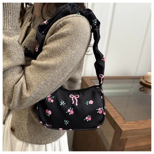 Floral black underarm bag with pink rose patterns and ruched strap shown on shoulder