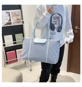 Detail of light blue nylon travel bag with PU leather handles shown by model in bright room