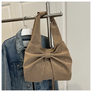 Detail of khaki shoulder bag with oversized bow and vintage faux leather texture